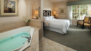 Ein Hotelzimmer mit Badewanne, einem Bett, einem Sessel und einem Fenster mit Blick.