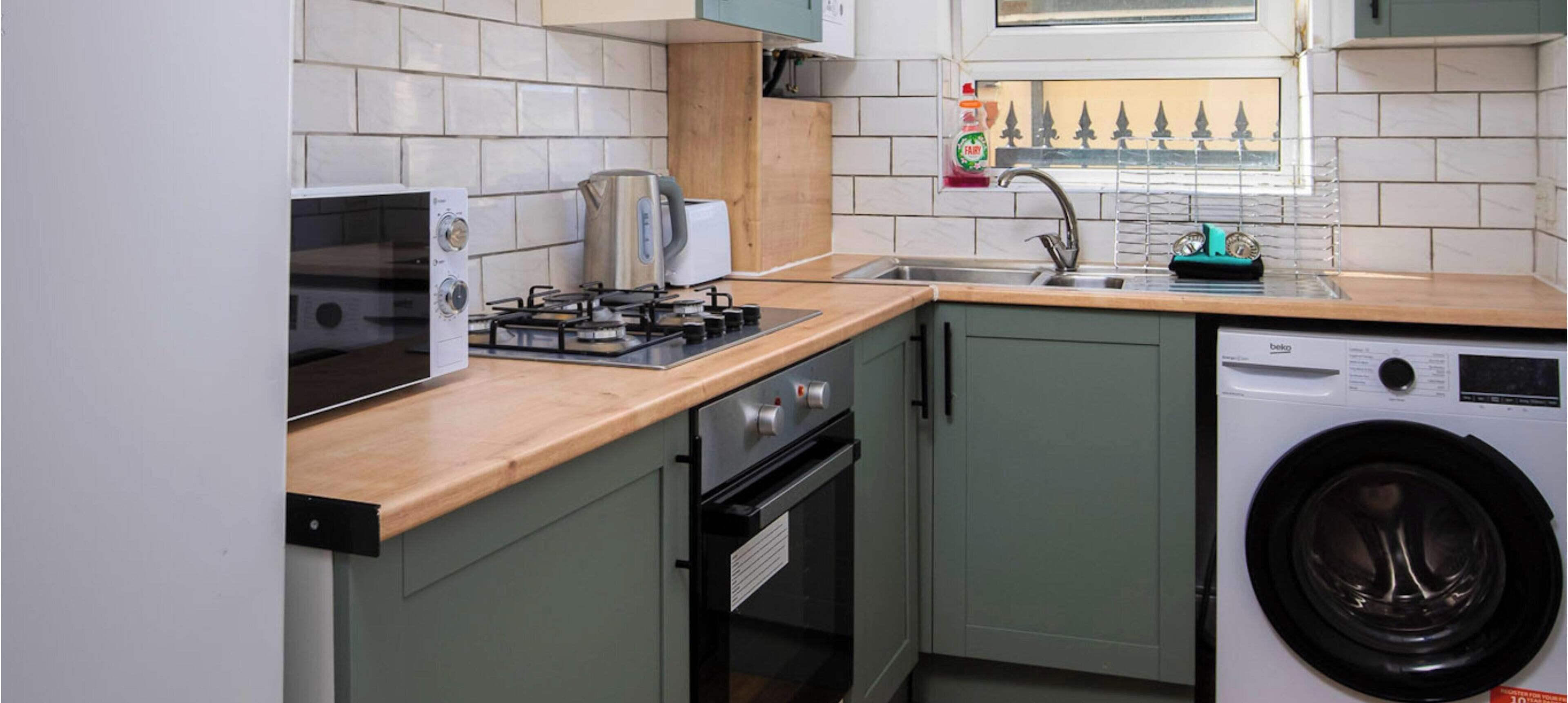 Una cocina compacta con lavadora integrada, microondas y cocina a gas.