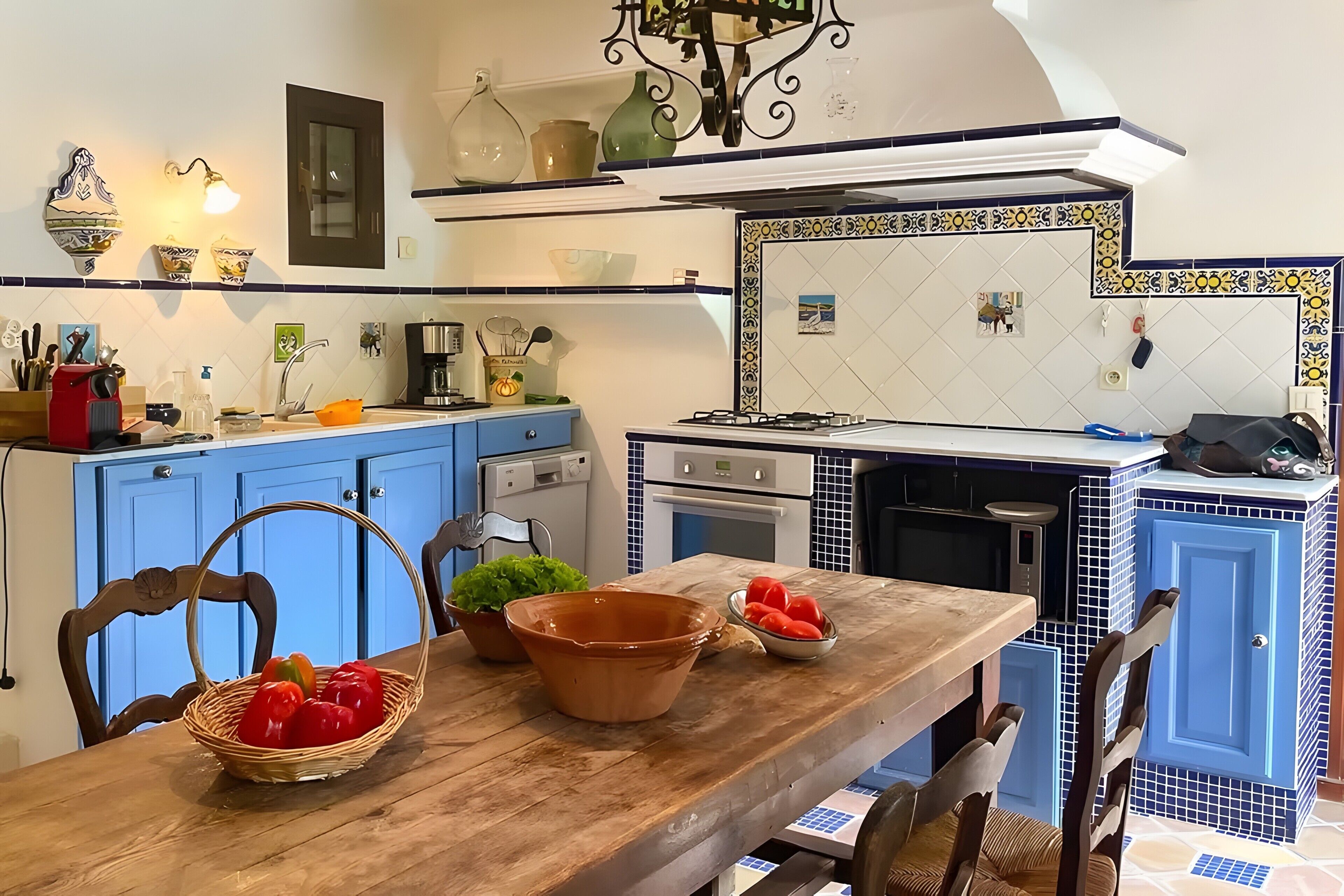A kitchen with blue cabinets, a wooden table, and various kitchen appliances.