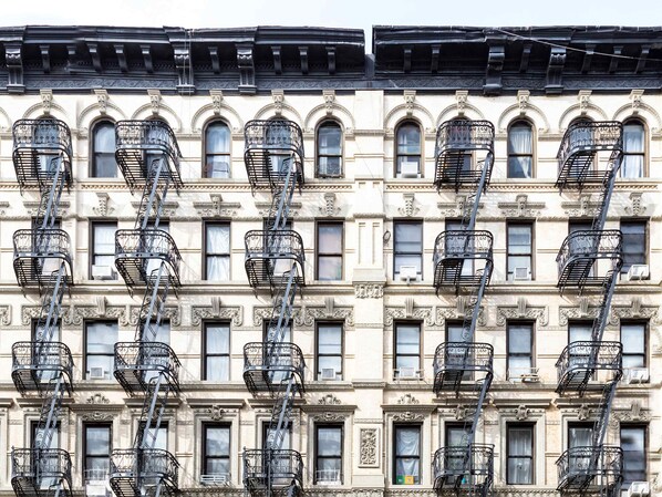 A row of multi-story buildings with ornate architectural details and fire escapes. - Hamilton House Apt 3 with Pvt Bath & Fireplace (New York)