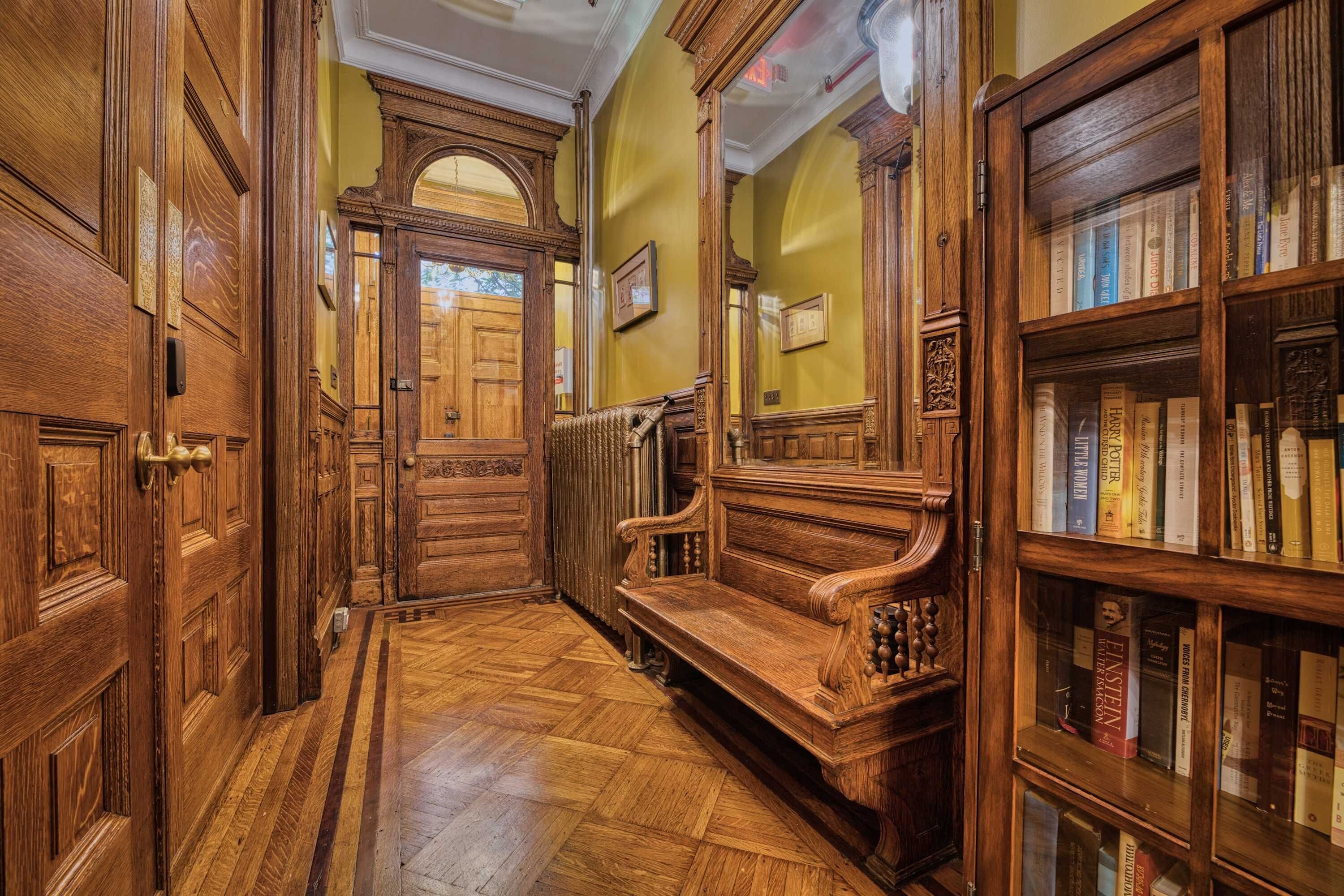 Ein Holzboden-Flur mit einer Bank und einem Bücherregal voller Bücher.