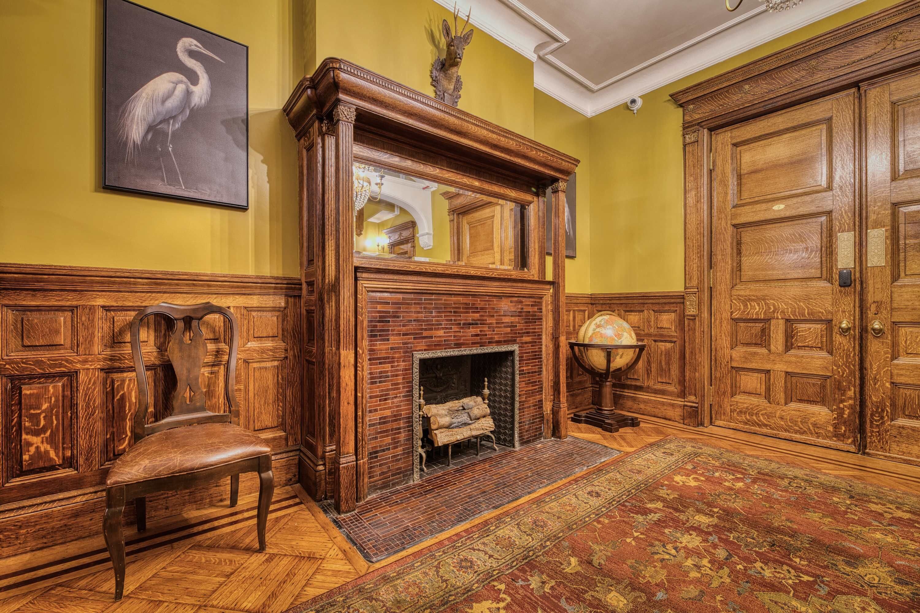 Una habitación con chimenea de madera, un banco, un tapete y una puerta.
