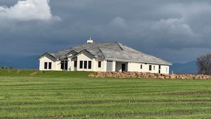Een gelijkvloers huis met een schuin dak, schoorsteen en een stenen fundering.