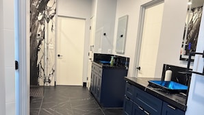 Een moderne keuken met donkere marmeren vloer, blauwe kastjes en een zwart aanrecht.