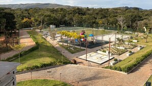 A playground with various play structures, surrounded by landscaped areas and a view of distant hills.