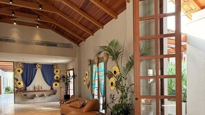 A spacious lobby with a high wooden ceiling, a large wooden-framed door, and a seating area with a brown sofa.