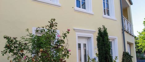 A two-story building with a yellow facade, white trim, and multiple windows.
