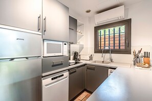 A modern kitchen with stainless steel appliances, a window with a view, and a built-in dishwasher. - Casa di Palombaggia - Appt avec belle vue mer (Porto-Vecchio)
