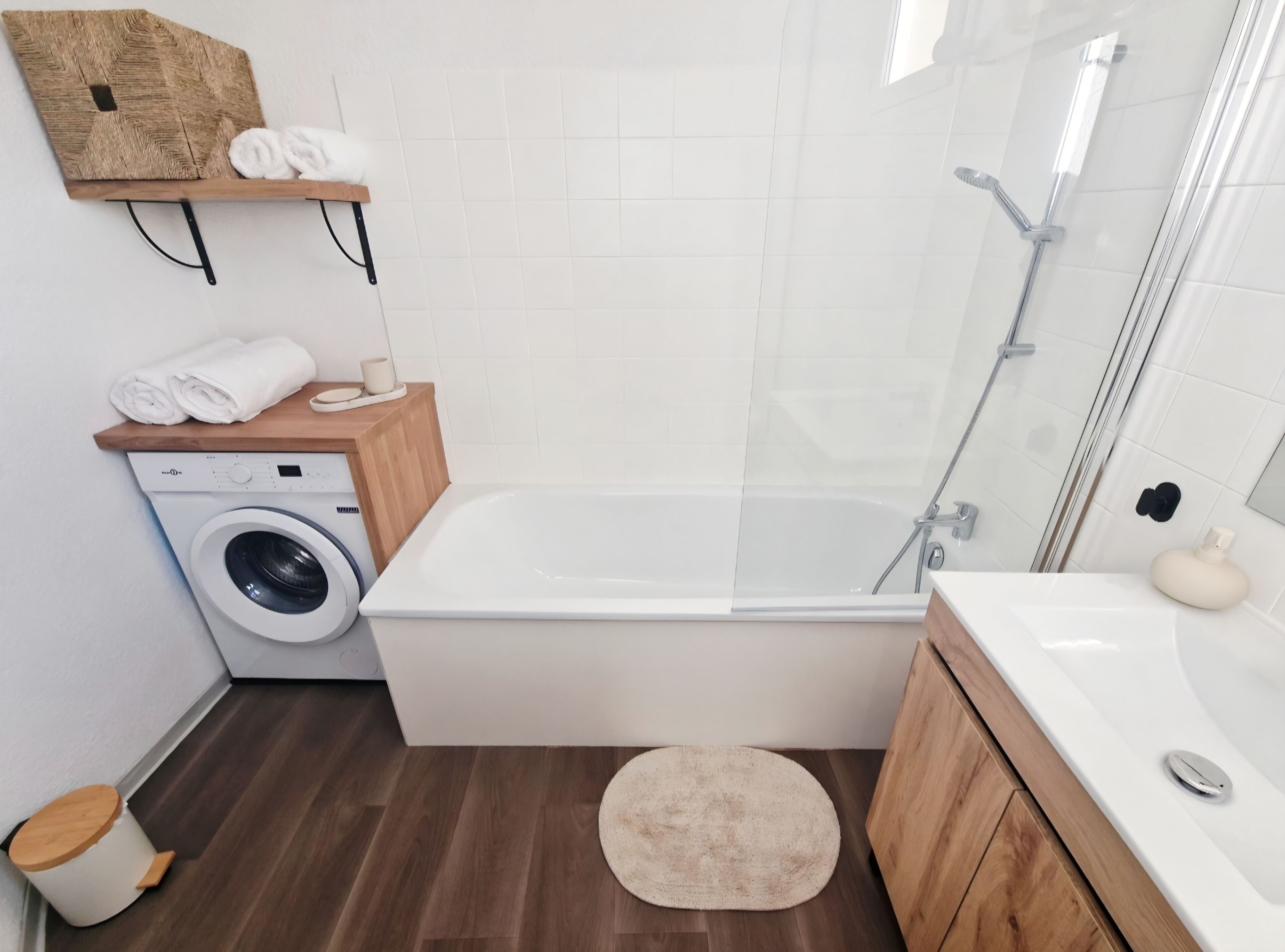 A modern bathroom with a washing machine, a bathtub, and a shower.