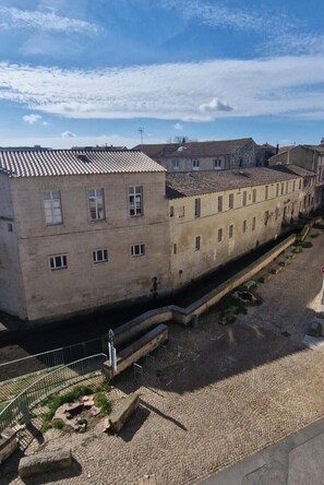 Un edificio con techo de tejas y varias ventanas, junto a un estrecho canal de agua.