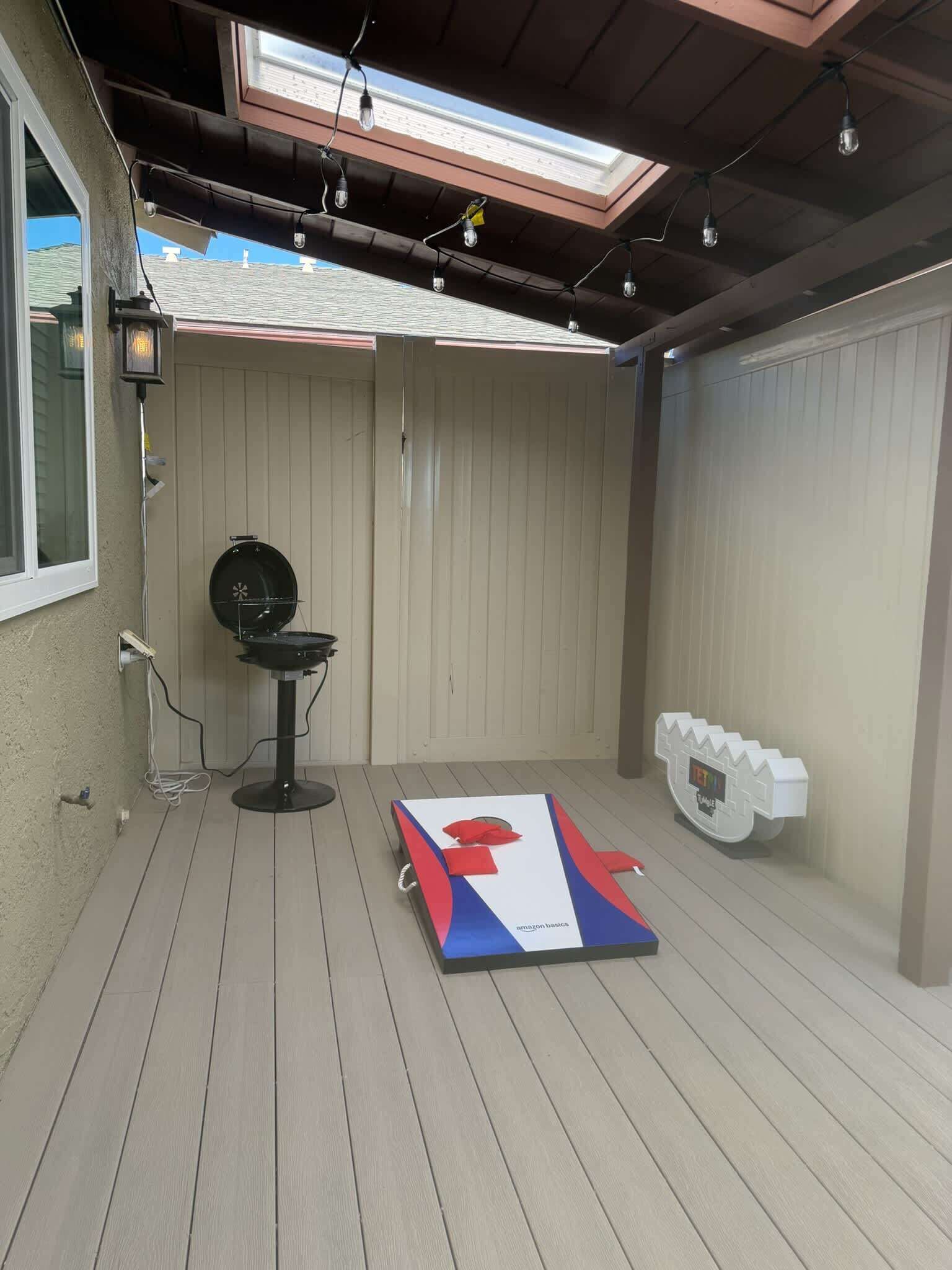 A covered patio area with a grill, a table with a red and blue tablecloth, and a white mailbox.