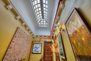A room with a skylight, a patterned rug, a framed painting, and a wooden door.