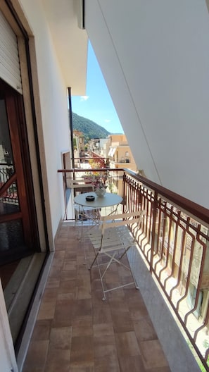 Uma varanda com mesa e cadeiras, vista para a cidade e uma montanha ao longe.