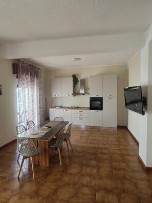 Eine moderne Küche mit weißen Schränken, einem eingebauten Backofen und einem an der Wand befestigten Flachbildfernseher.
