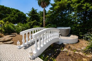 A white wrought iron bridge, a stone pathway, and a hot tub in a garden setting. - Villa Paraiso | 6 bedrooms | Jacuzzi | Carvoeiro (Carvoeiro)