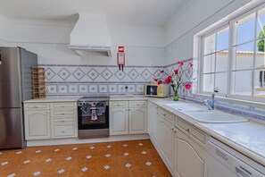 A kitchen with white cabinets, a stainless steel refrigerator, a microwave, and a sink. - Villa Paraiso | 6 bedrooms | Jacuzzi | Carvoeiro (Carvoeiro)