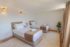 Ein Hotelzimmer mit zwei Betten, einem Nachttisch, einer Lampe, einer Topfpflanze und einem Vorhang.