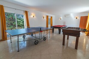 Ein Raum mit Tischtennisplatte, Kicker und Billardtisch.