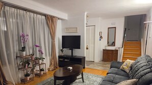 Ein Wohnzimmer mit einer Couch, einem Couchtisch, einem Fernseher und einer Treppe zu einer weiteren Ebene.