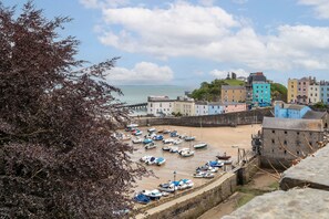 A coastal town with a sandy beach, a stone wall, and several colorful buildings. - Tenby Harbour View - Heart of Tenby, Sea Views (Tenby)