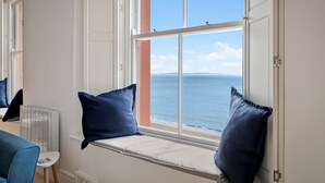 Une pièce avec un coin fenêtre, un radiateur et une vue sur la mer.