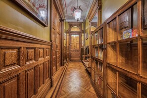 Un pasillo de madera con puertas ornamentadas y un candelabro.