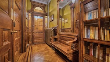 A wooden hallway with a bench and a bookshelf filled with books.