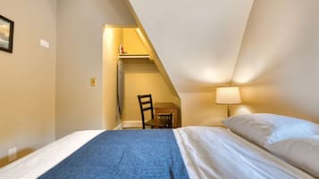 Ein Schlafzimmer mit Bett, Stuhl, Schreibtisch und Lampe.