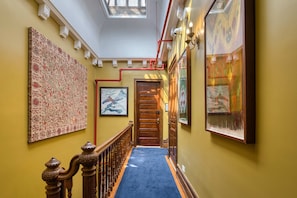 A hallway with a wooden staircase, a blue carpet, and artwork on the walls. - Hamilton House Apt 7 with Pvt Bathroom (New York)