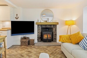 A living room with a fireplace, a television, a sofa, and a lamp. - Rose Cottage - Sea Views, Hot Tub, Log Burner (Pendine)