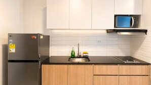 Een keuken met een roestvrijstalen koelkast, een magnetron, houten keukenkastjes en een betegelde spatwand.
