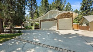 A residential driveway with a garage, surrounded by trees and a well-maintained lawn. - Walk to Snow Summit, AC, Fenced Yard (Big Bear Lake)