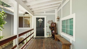 A covered porch with a wooden bench, a door with a wreath, and a small table with a lantern. - Walk to Snow Summit, AC, Fenced Yard (Big Bear Lake)