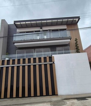 A modern two-story building with a balcony, a gated entrance, and a concrete facade. - COPERIA PREMIUM (Cuenca)