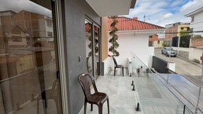A balcony with a chair, a potted plant, and a view of neighboring buildings. - COPERIA PREMIUM (Cuenca)