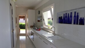 Une cuisine avec des meubles blancs, un évier et une fenêtre donnant sur un paysage verdoyant.