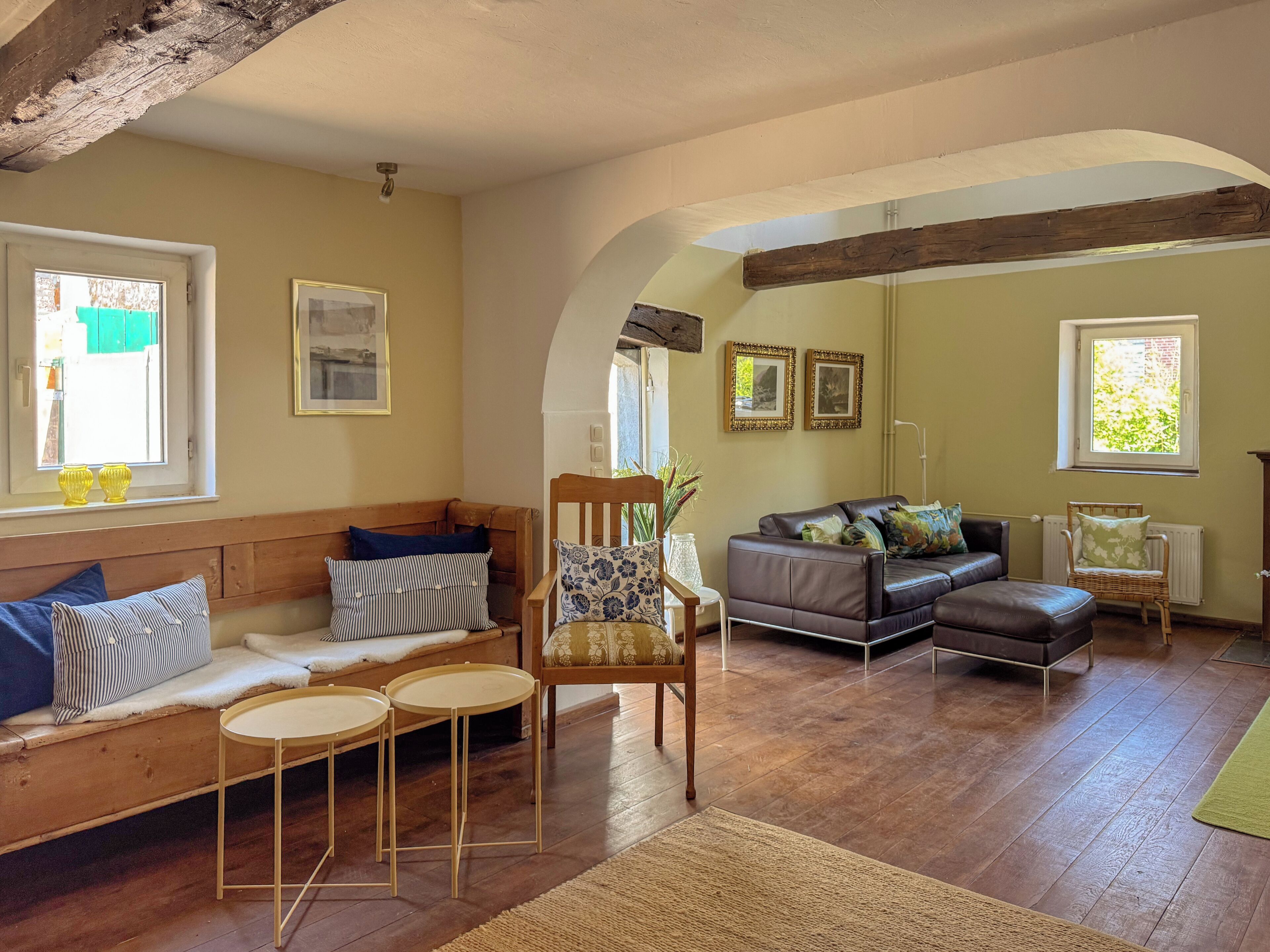 Un salón acogedor con suelo de madera, un sofá, una silla y una mesita.