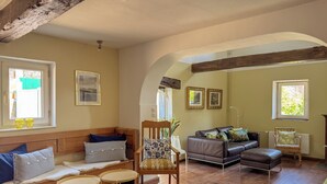 Un salón acogedor con suelo de madera, un sofá, una silla y una mesita.