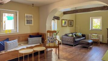 Un salón acogedor con suelo de madera, un sofá, una silla y una mesita.