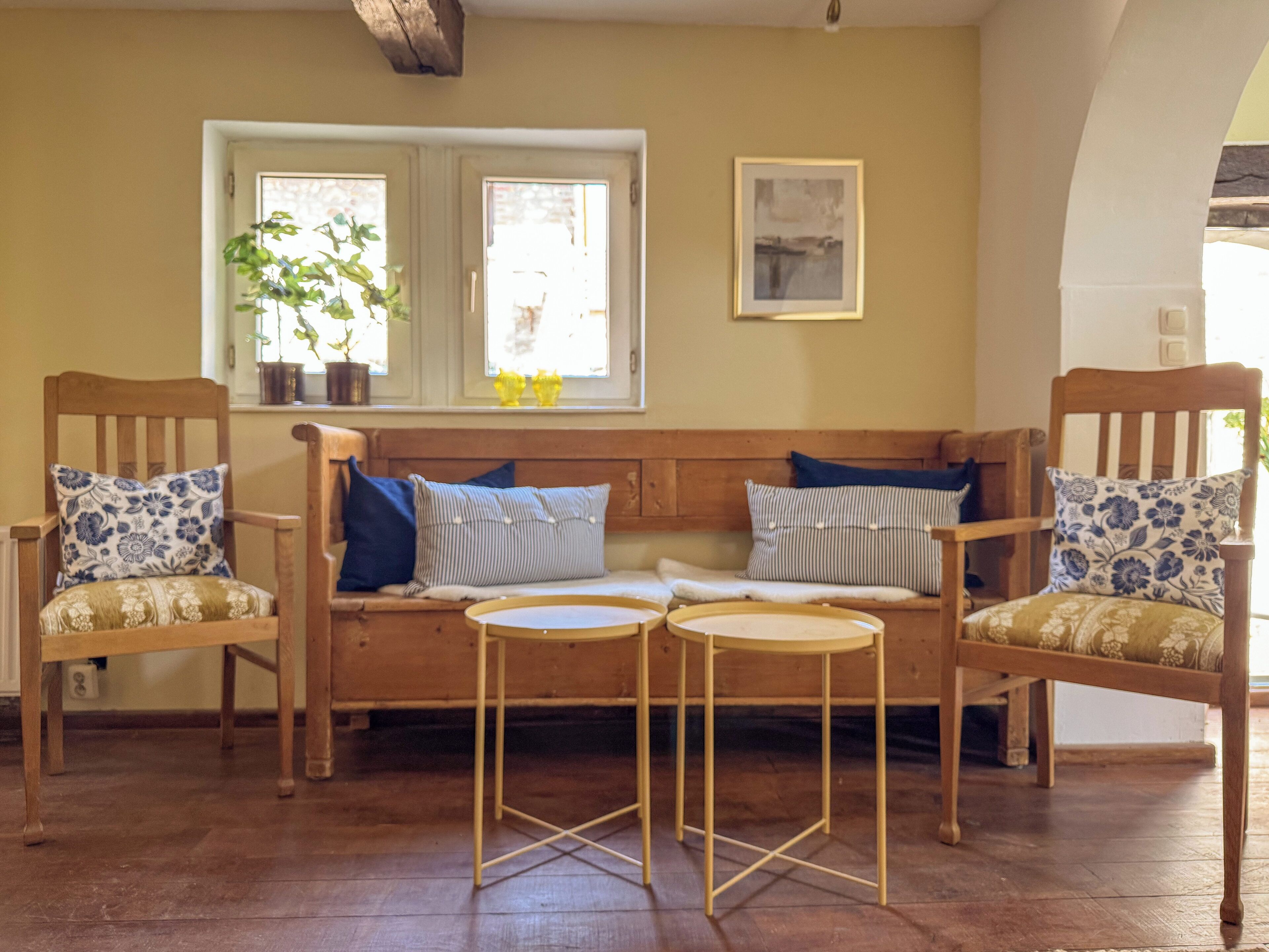 Une pièce chaleureuse avec un canapé en bois, deux fauteuils et une petite table ronde.
