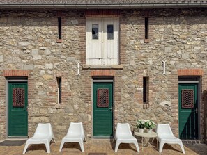 A stone building with three green doors, each with a decorative grille, and white plastic chairs outside. - 10P 6B Authentic stone house near Maastricht (Dalhem)