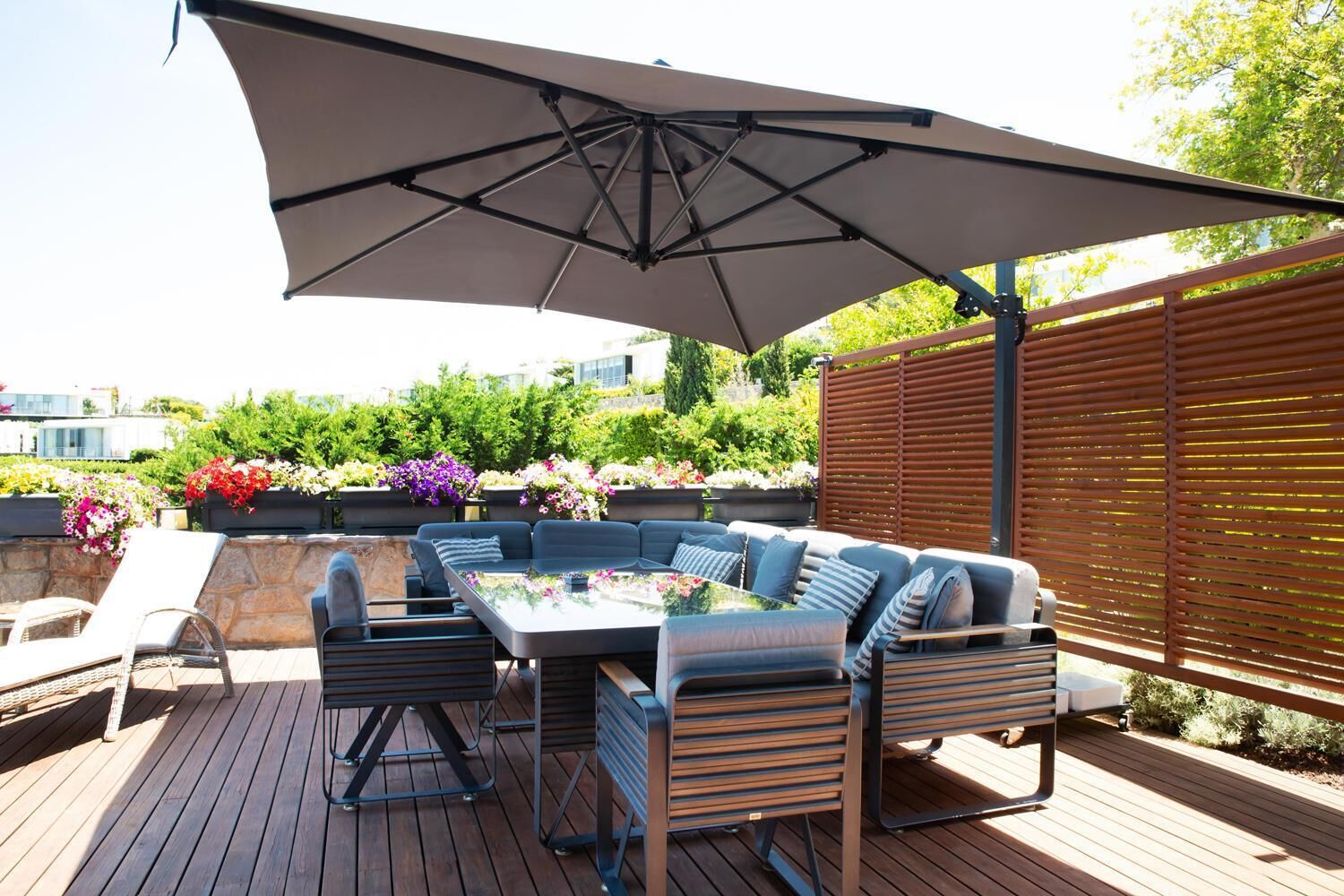 An outdoor patio with a table and chairs, a large umbrella, and a wooden deck.