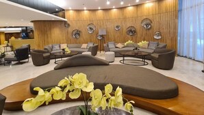 Eine moderne Lobby mit einer geschwungenen Sitzecke, Holzvertäfelung und einem zentralen Kronleuchter.
