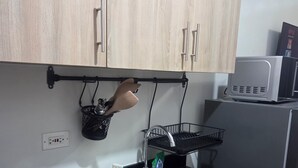 Eine Küche mit Holzausstattung, einer schwarzen Arbeitsplatte, einem Edelstahlspülbecken, einer Mikrowelle und einem schwarzen Hängegestell für Kochutensilien.