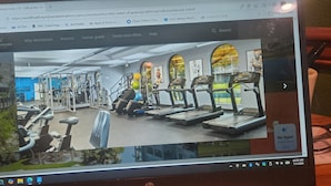A gym with exercise equipment, a treadmill, and a person using a machine.