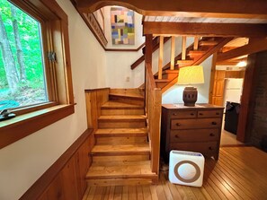 Een houten trap leidt naar een keuken met een wasmachine en een lamp op een nachtkastje.