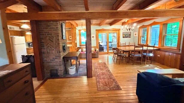A wooden interior with a dining area, kitchen, and a fireplace.