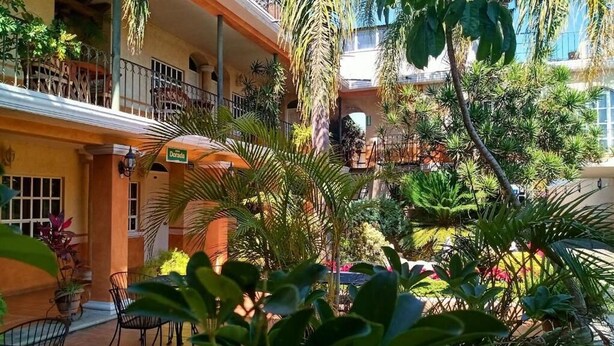 A courtyard with outdoor seating, potted plants, and a building with balconies. - HOTEL MEZVALL (Morelia)