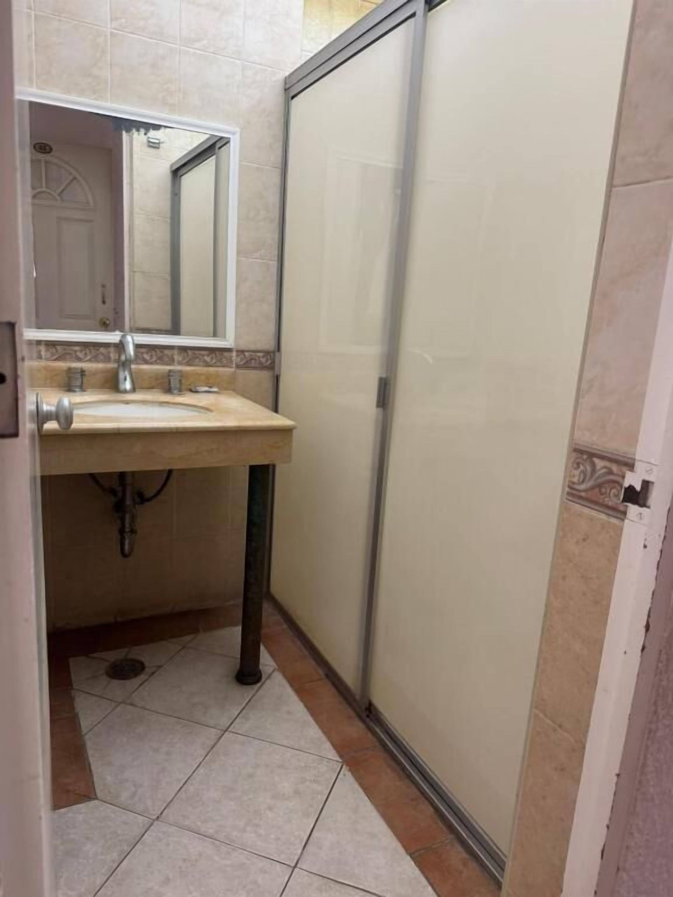 Baño con lavabo, espejo y cabina de ducha.