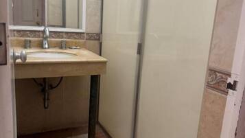 Baño con lavabo, espejo y cabina de ducha.